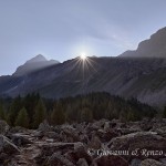Il sole fa capolino dalle montagne e fasci di luce illuminano il Pizzo Scalino